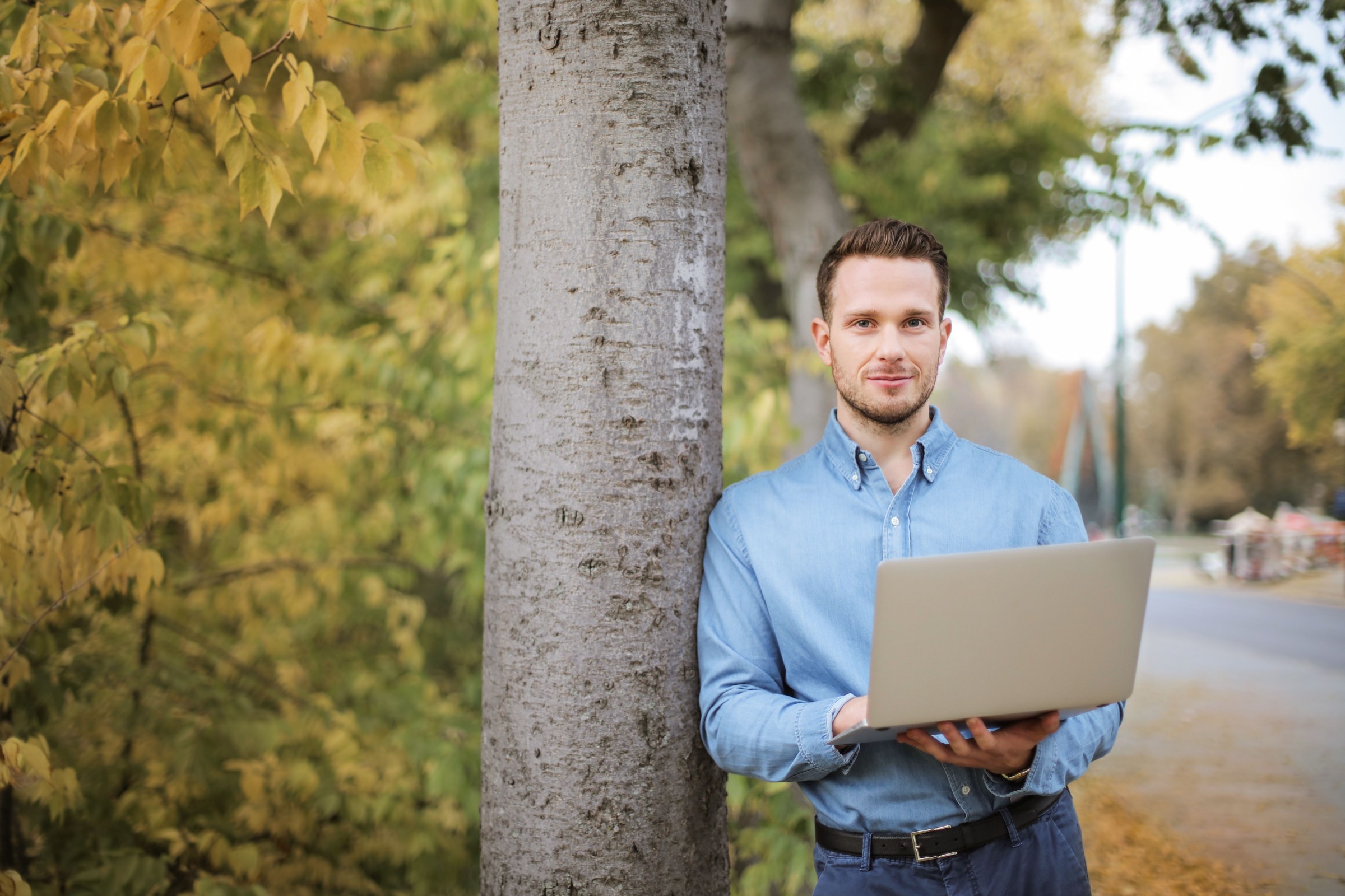 Freelancer holding a laptop beside a tree